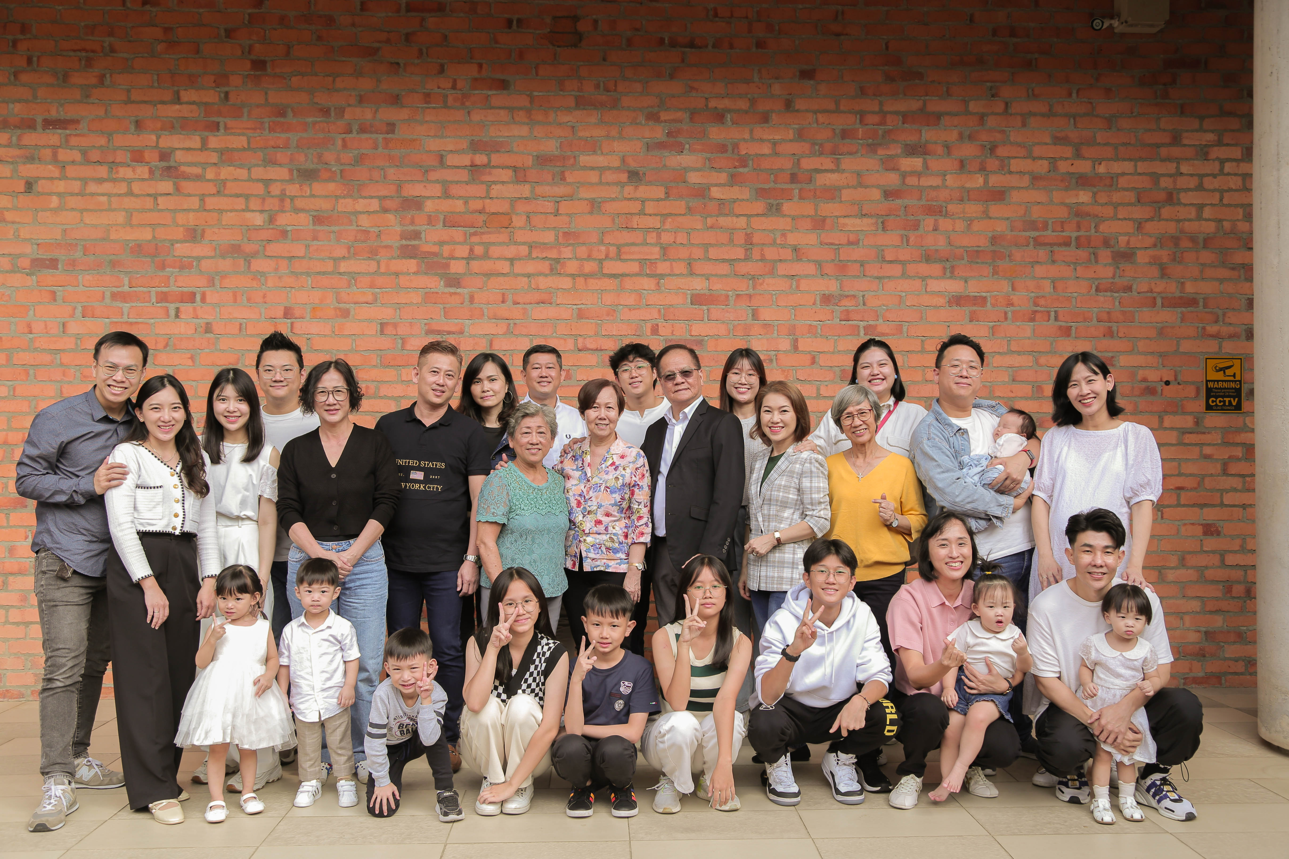 陈丽玉姐妹带领两位妹妹信主。多年来，这个家族在喜信堂扎根成长，枝叶茂盛、信仰传承。图为家族成员与黄雅各牧师（第二排右五）及罗艳兰师母（右六）合影。